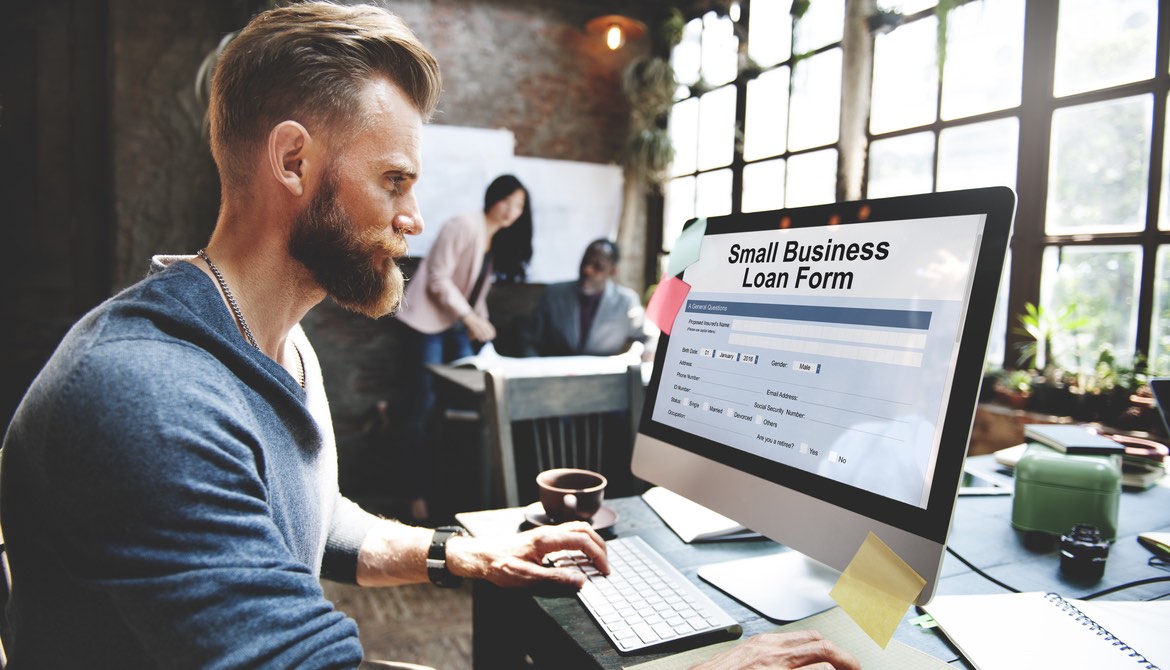 man looking at business loan form on computer screen