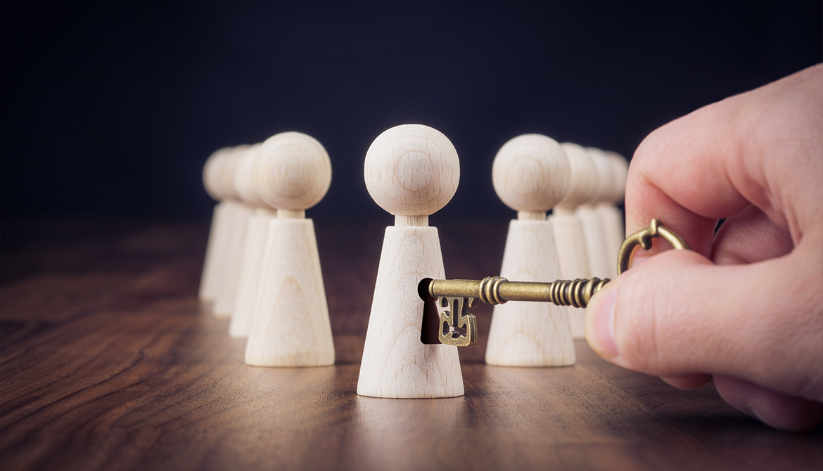 hand reaching out with a key to unlock the potential of one of several figurines representing employees