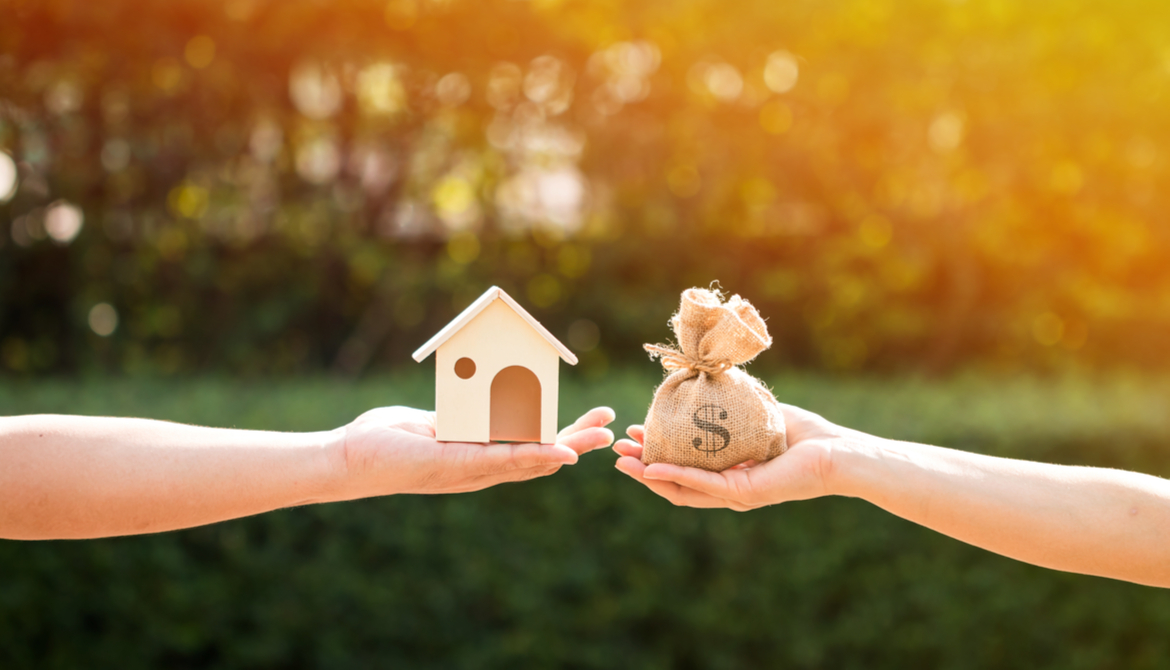 a man and a women hand holding a money bag and a toy-sized model home