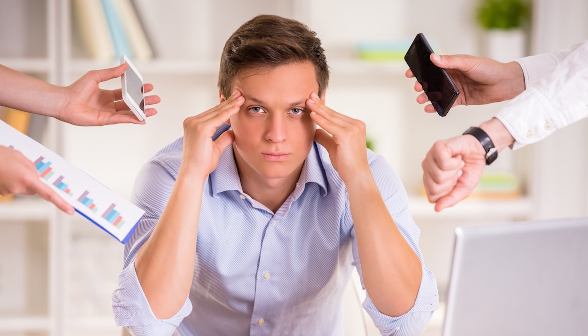 Stressed manager in his office being asked to do too many tasks at once