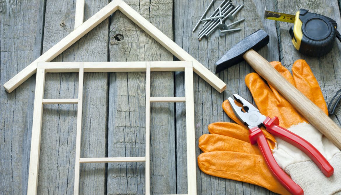 model wood frame of a house with tools lying next to it on a wood table