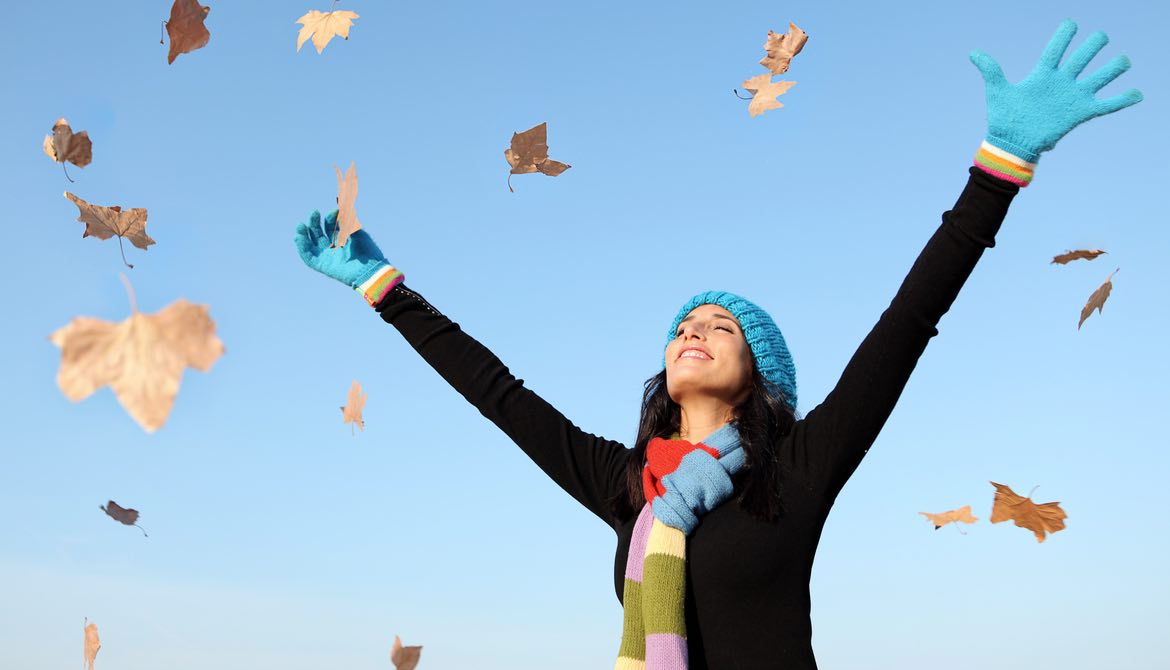 woman throwing fall leaves in the air