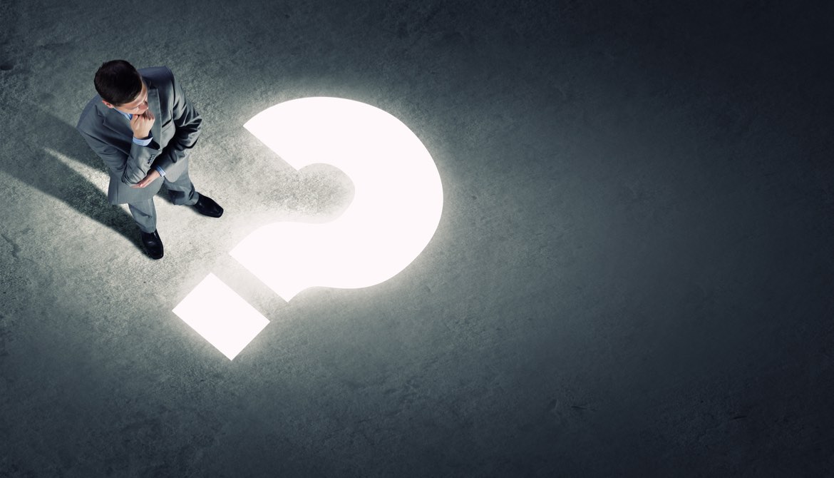 business man standing in shadow with a lit question mark in front of him