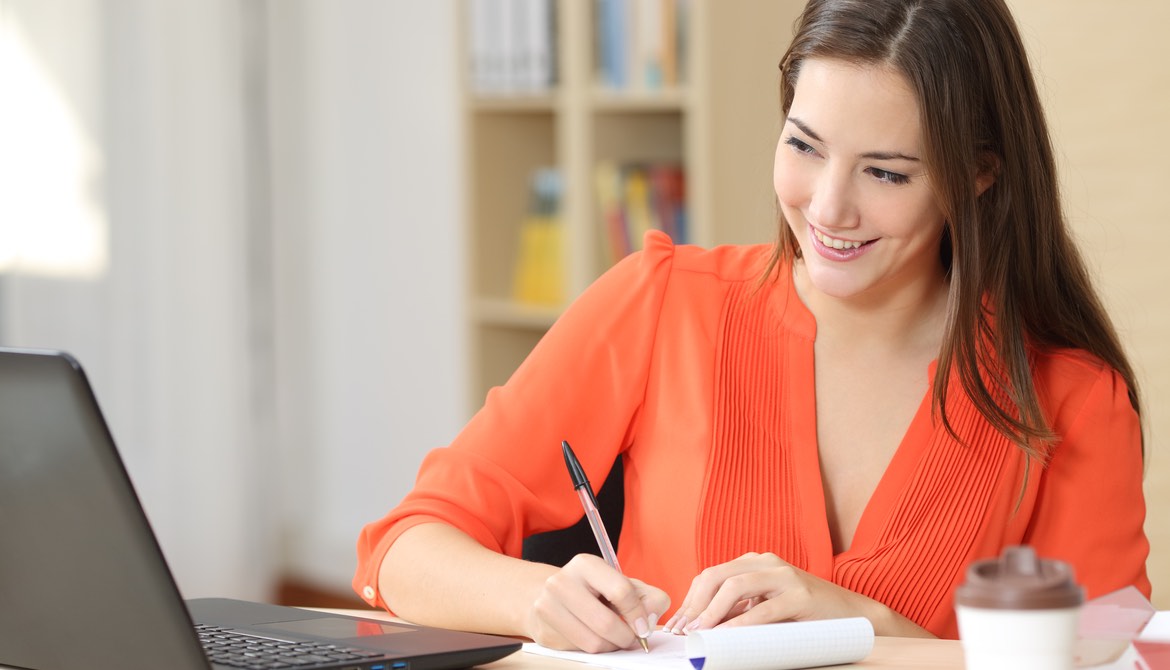 young woman in a bright orange blouse writing