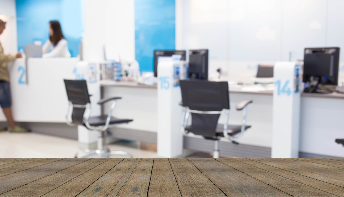 blurred image of a bank credit union lobby over a wooden desk