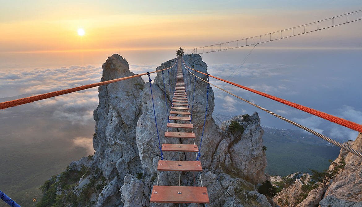 Precarious rope bridge leading to a mountain peak