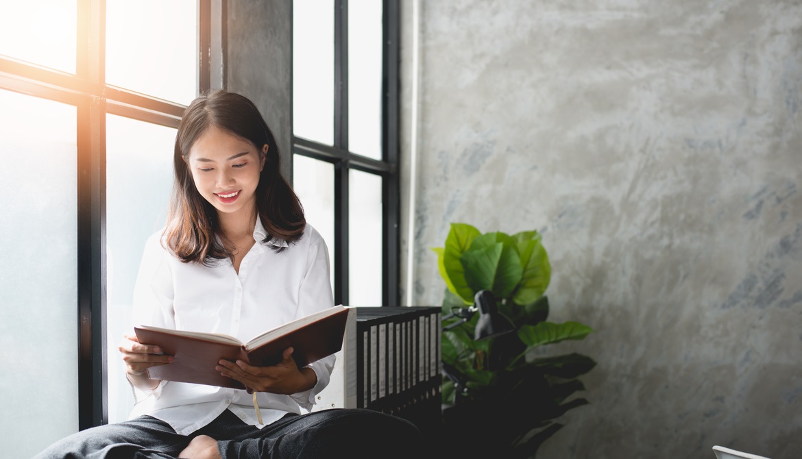 young Asian businesswoman reading by office window