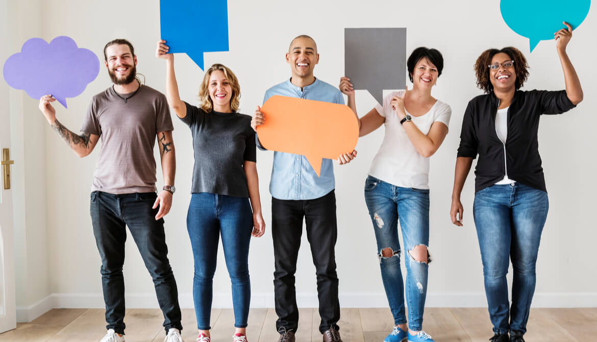 diverse employees standing holding up paper conversation bubbles of different shapes and sizes