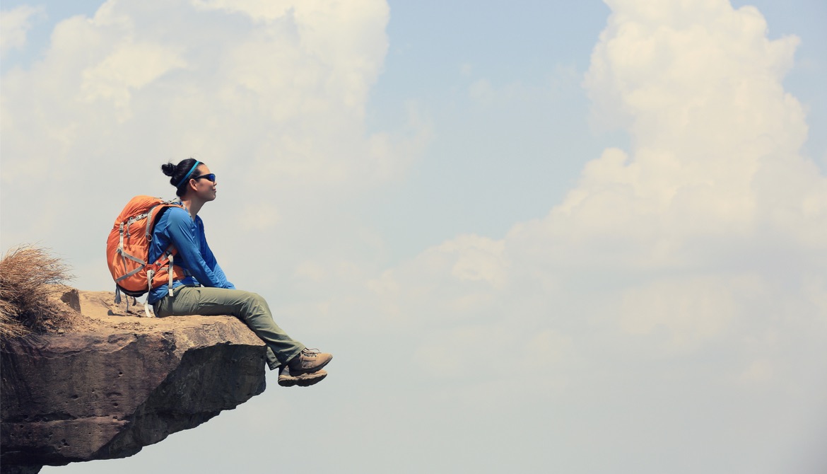 confident pensive hiker sitting on the edge of a cliff