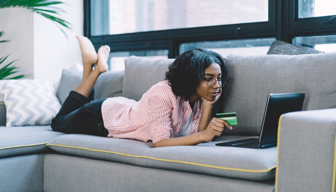 young African American woman using credit card and laptop