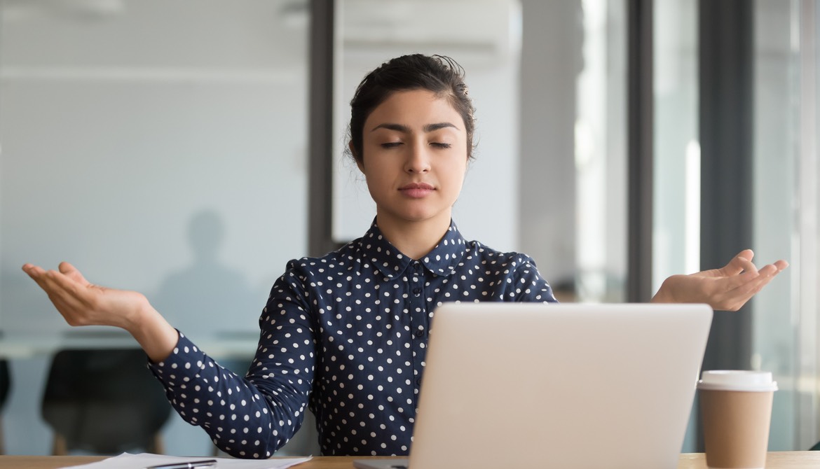 female executive meditating at her desk