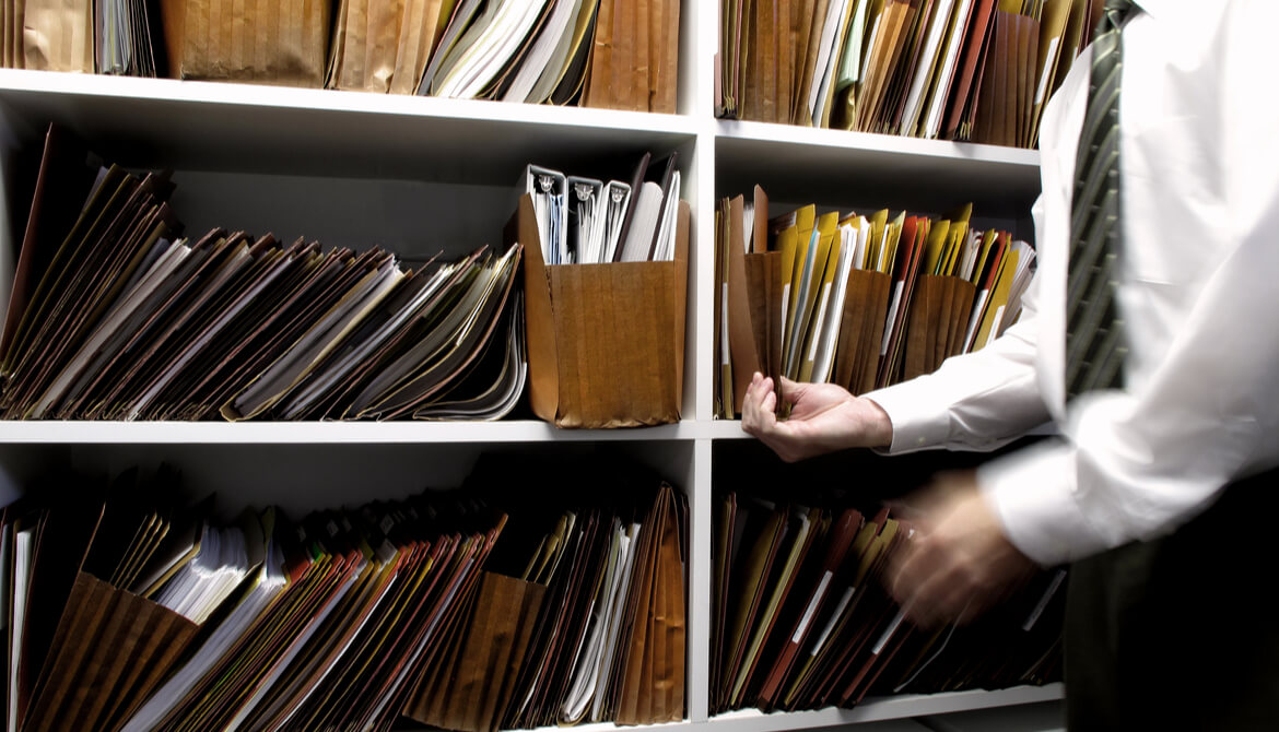 man retrieves old file off shelves