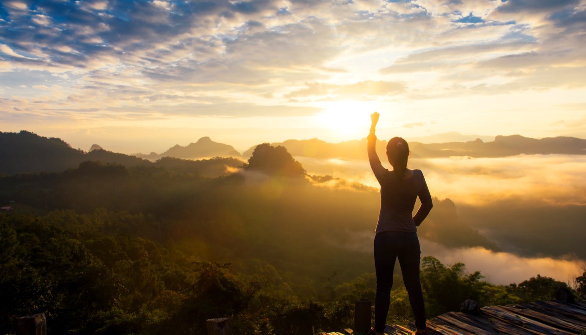 woman in sunset at top of mountain