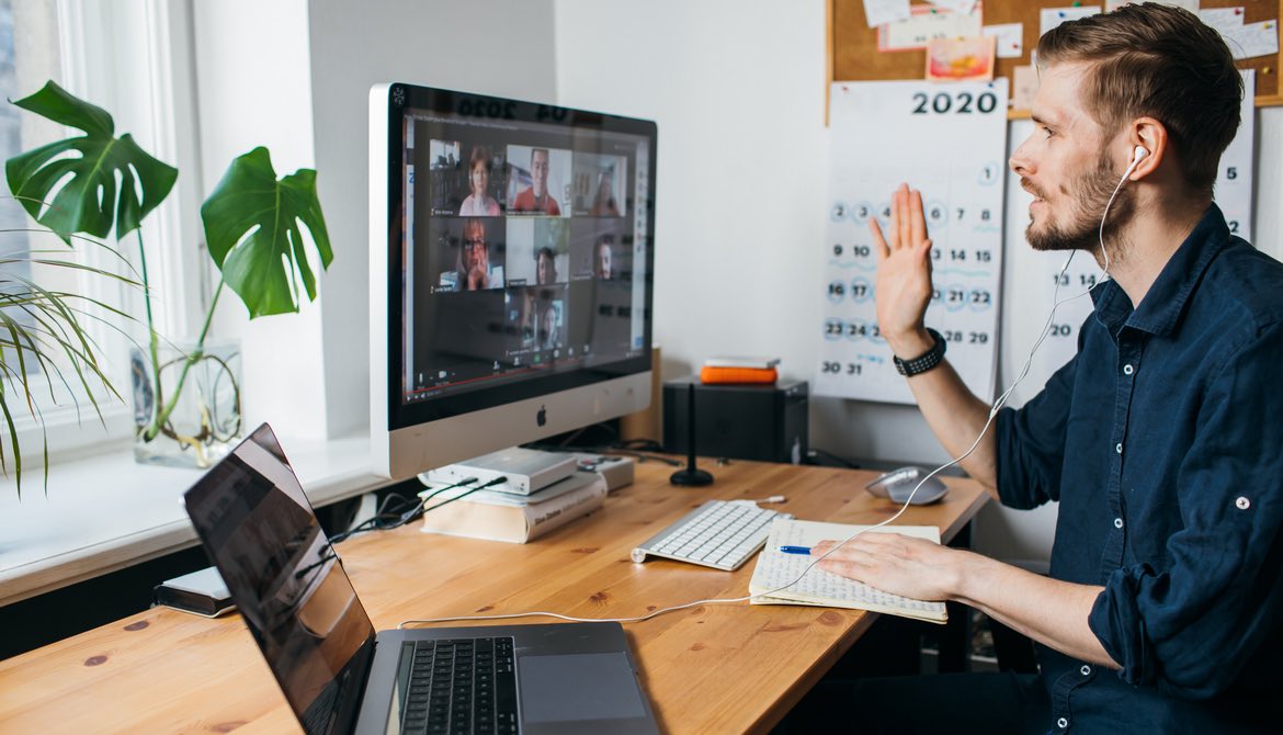 young male employee video conferencing with coworkers