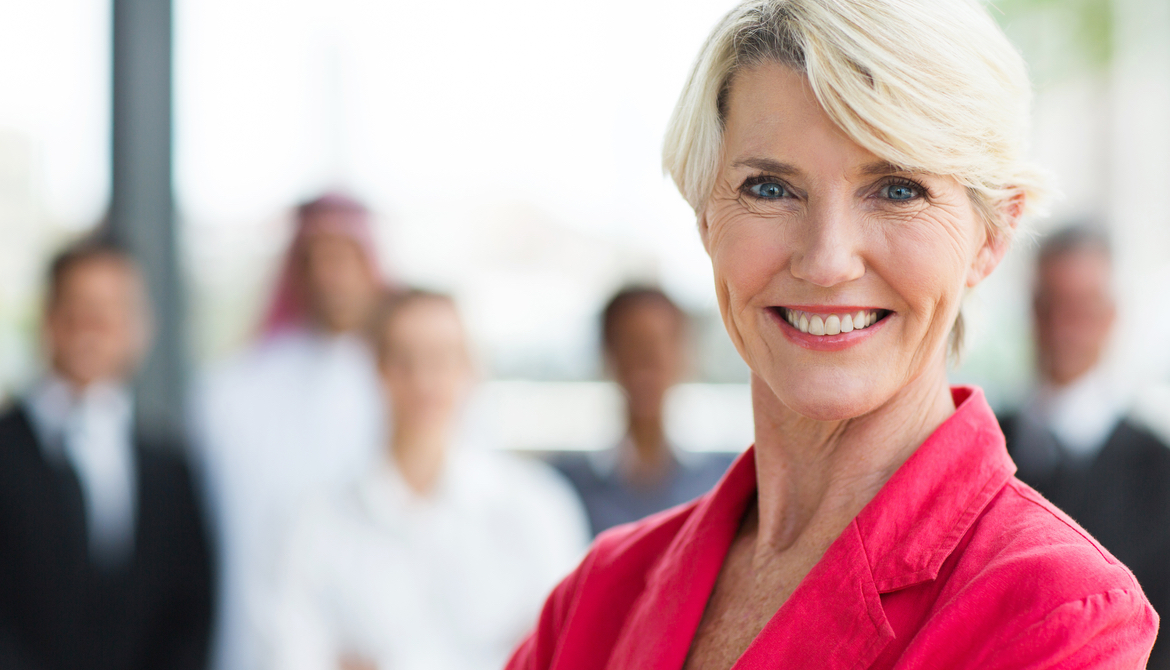 smiling senior female board member in pink blazer