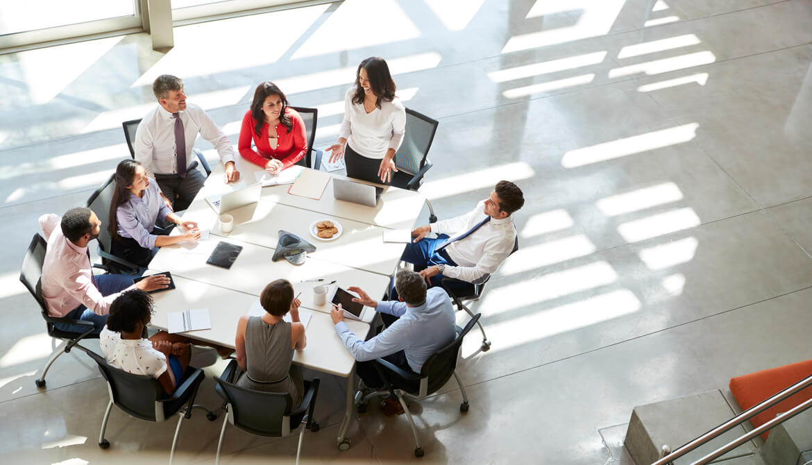 smiling businesswoman engages team of diverse people around meeting table