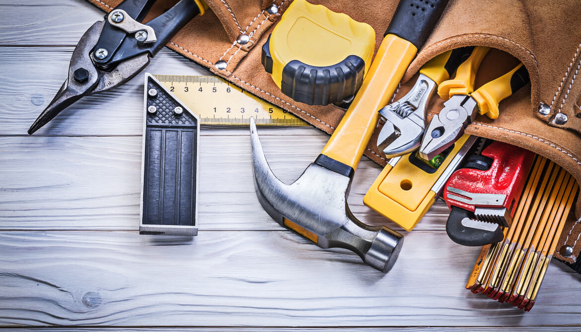 hammer and leather belt with pouches full of tools on wood surface