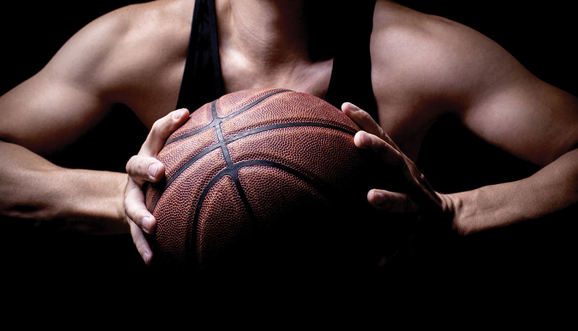 muscular athlete holding basketball in both hands preparing to pass