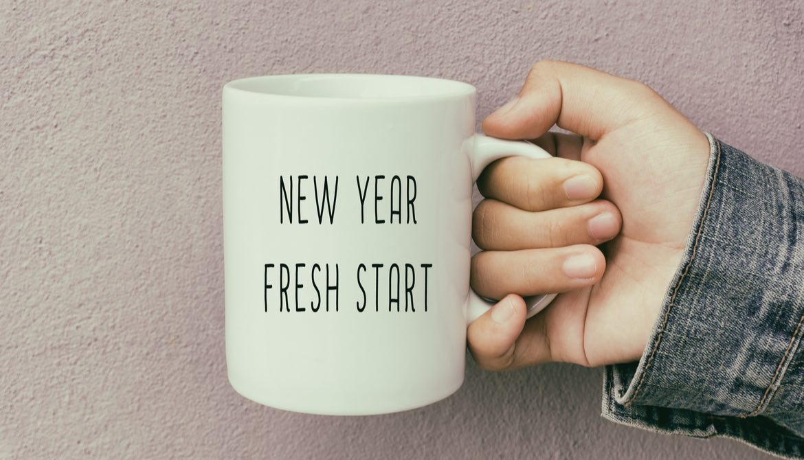 person in jean jacket holding mug with words new year fresh start written on it