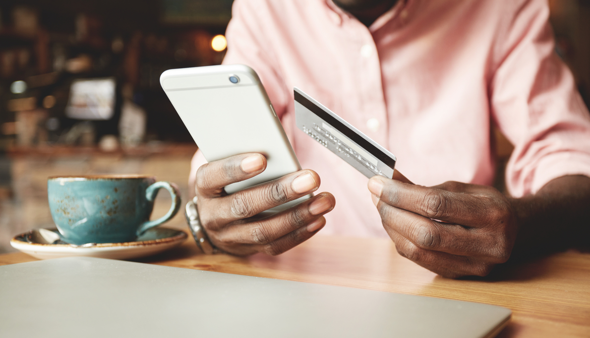 man in a pink shirt in a coffee house making a payment