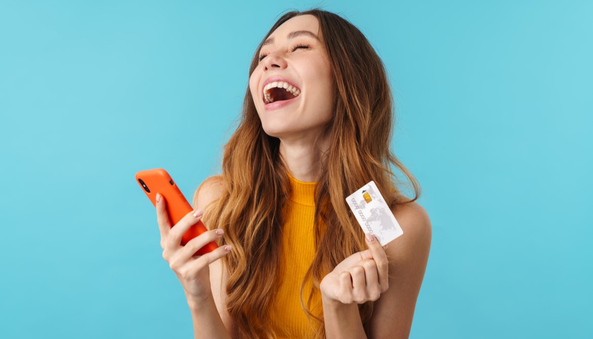 delighted woman with credit card and smartphone