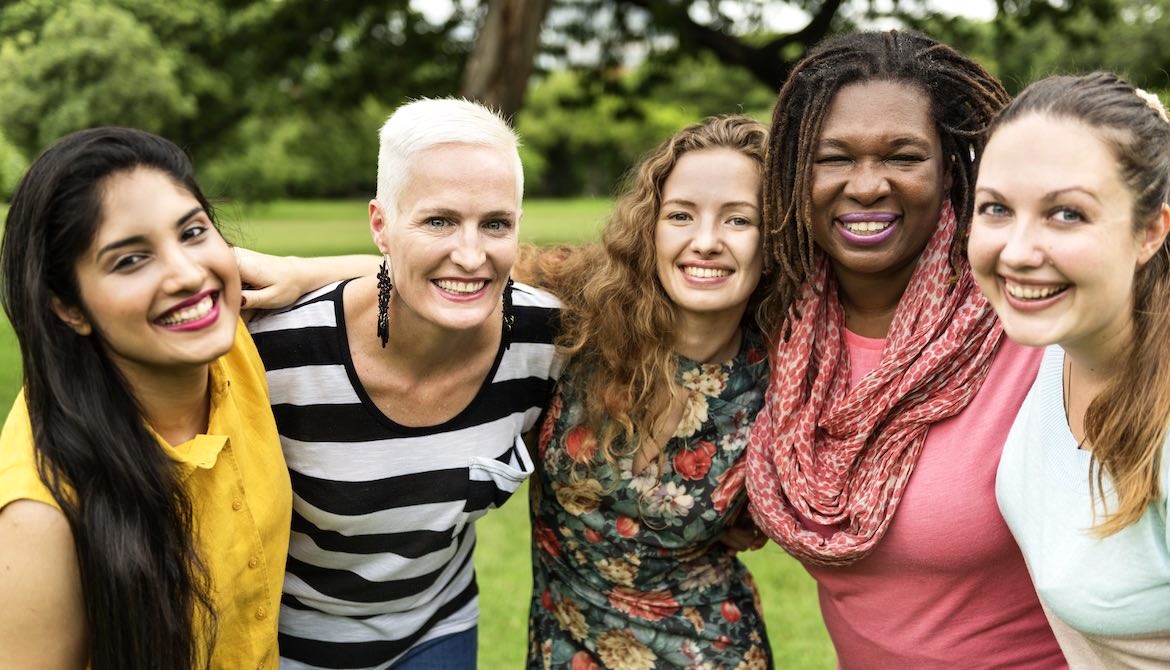 diverse group of women with arms around each other being supportive