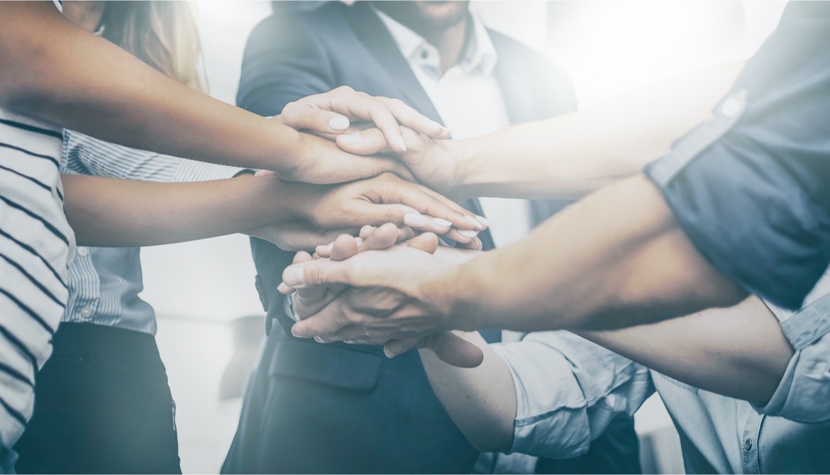 businesspeople stacking their hands together to show team unity and trust