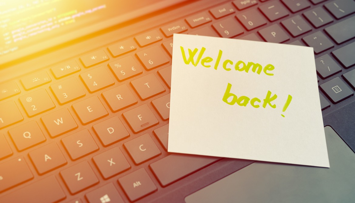 welcome back written on sticky note stuck to open laptop keyboard