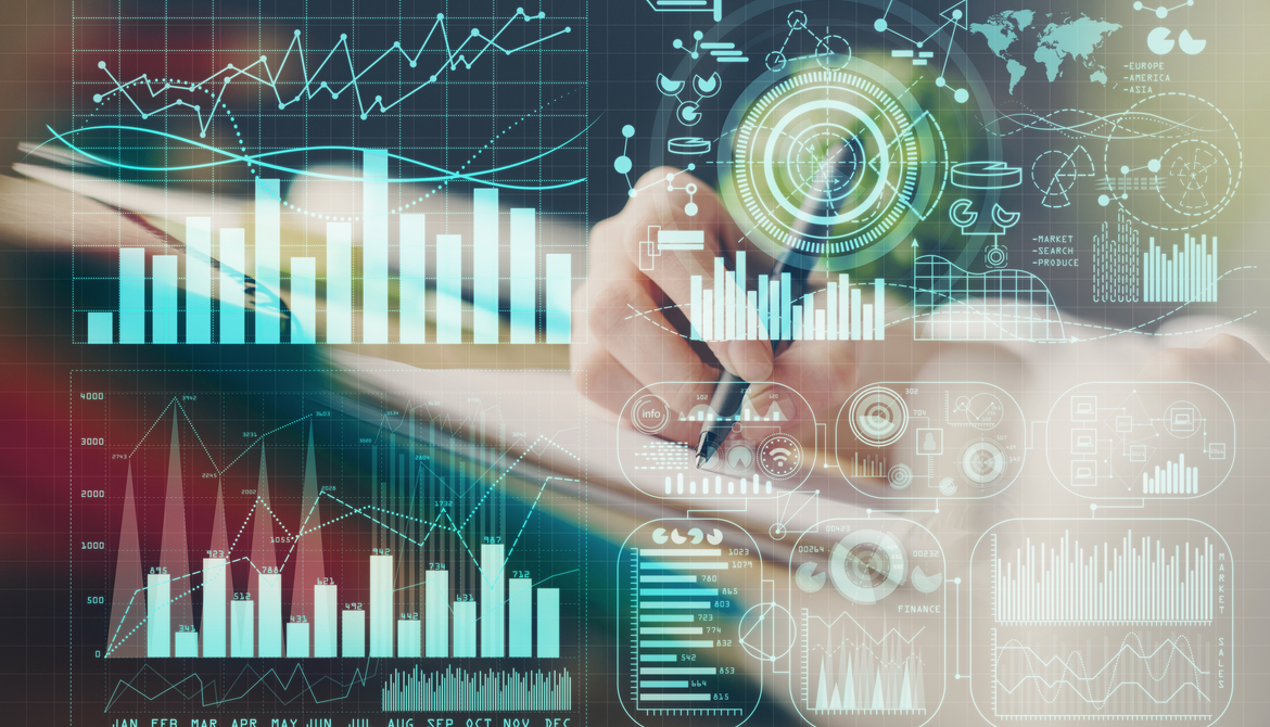 many digital financial graphs and charts displayed in front of hand taking notes in background