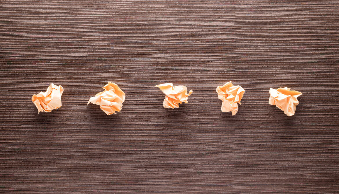 five crumpled pieces of paper on table