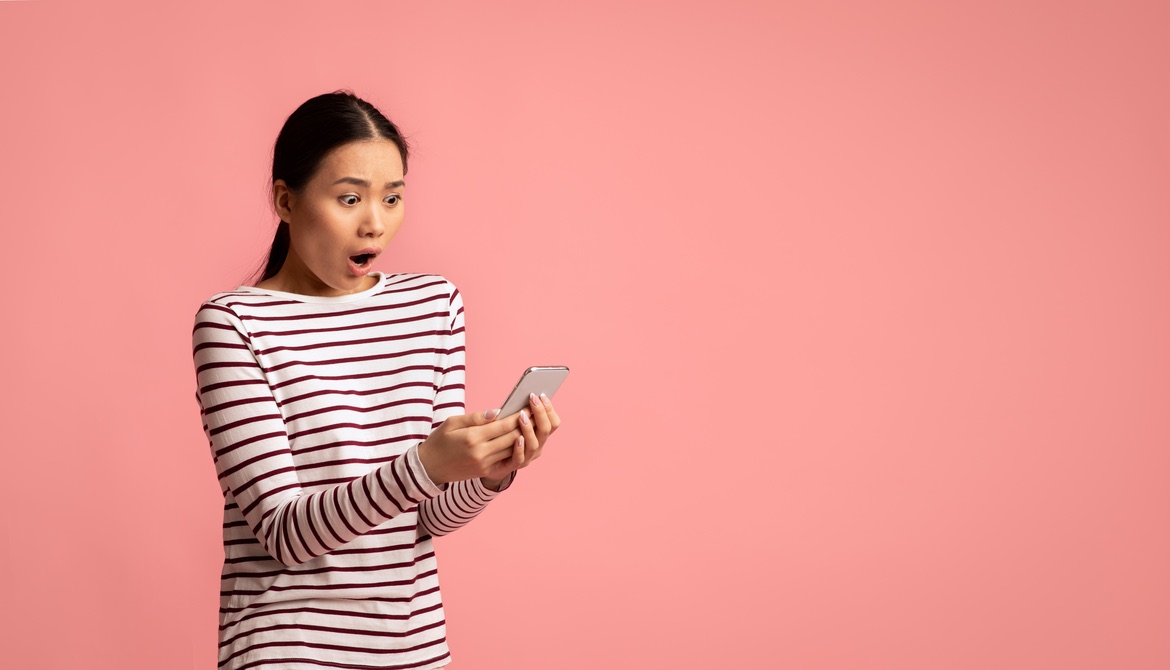 young person looking unhappily surprised while holding phone