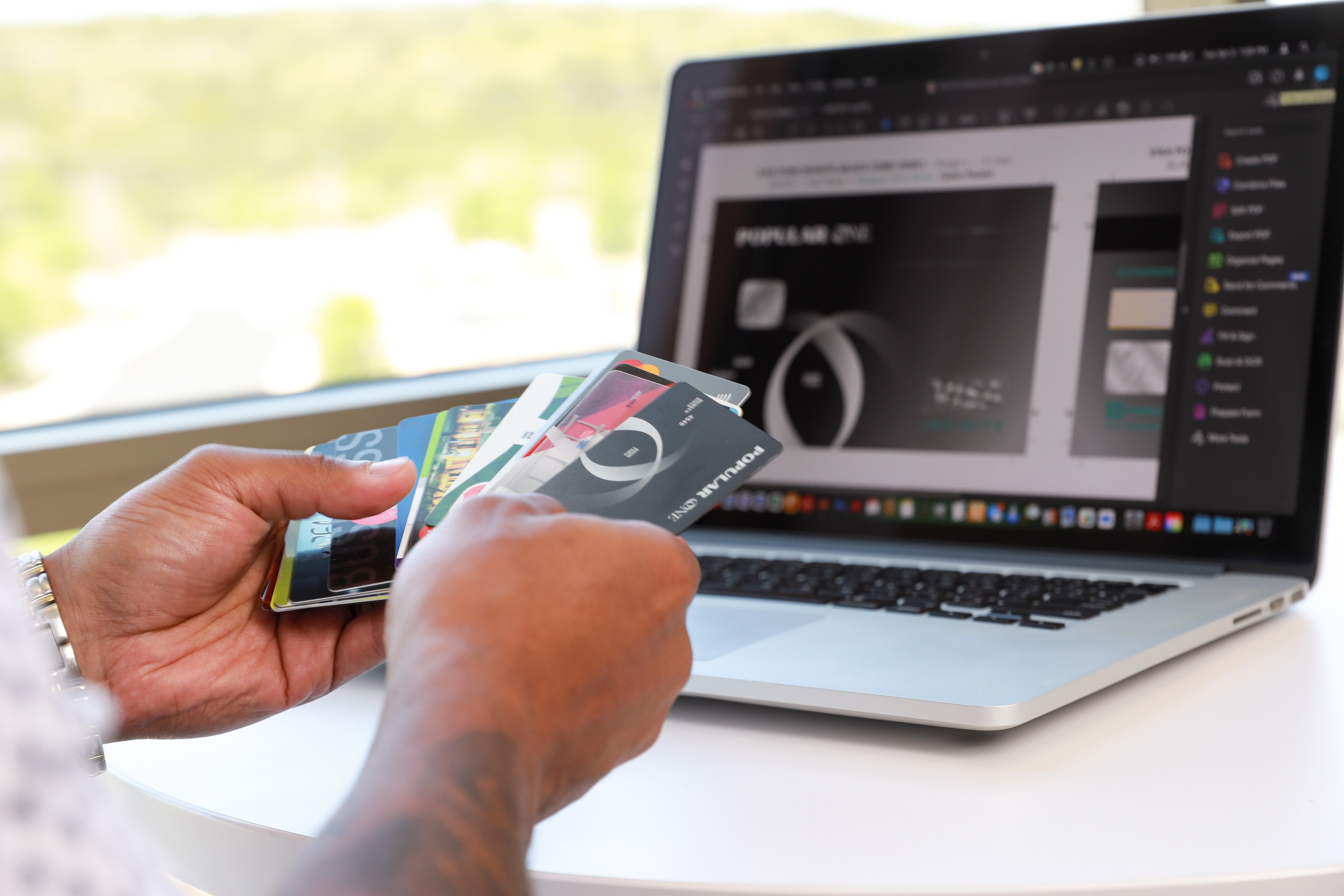 Josh Hatcher of Vericast reviews customized payments cards in front of laptop displaying design software