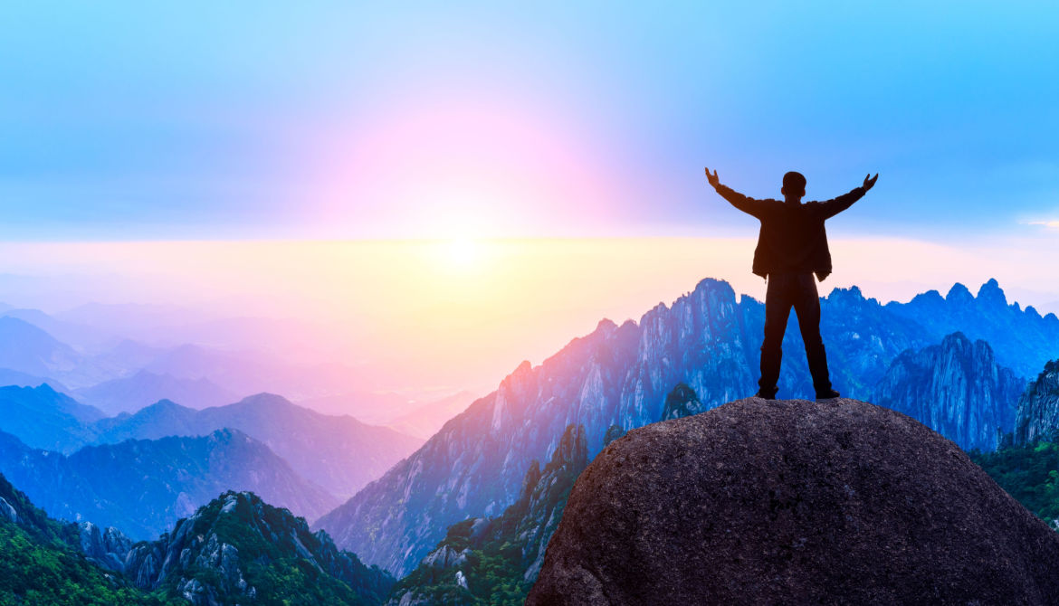 man with outstretched arms atop mountain