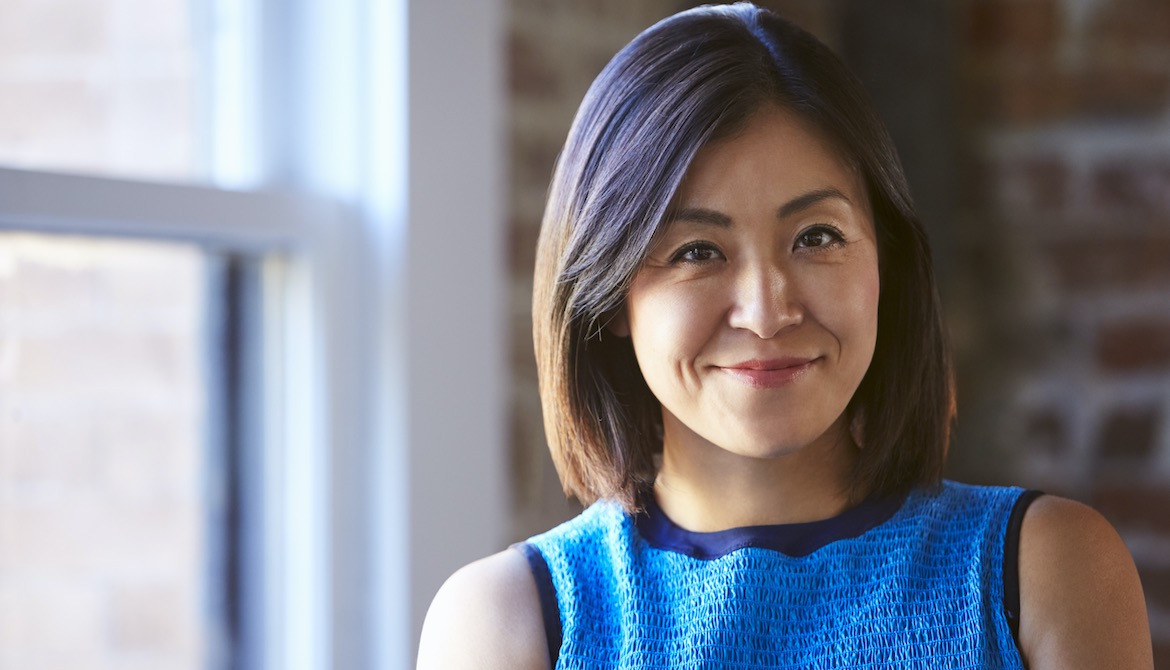 businesswoman CEO standing by office window smiles confidently