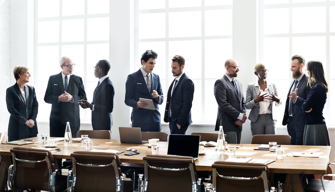 diverse group of board members mingles after meeting