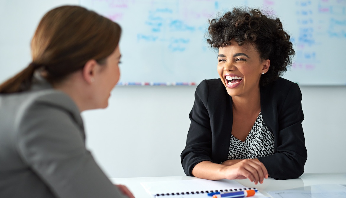 female colleagues in office laugh together during a meeting showing great rapport