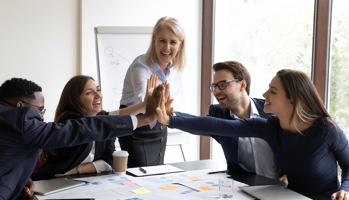 diverse team of celebrating young employees high five with manager