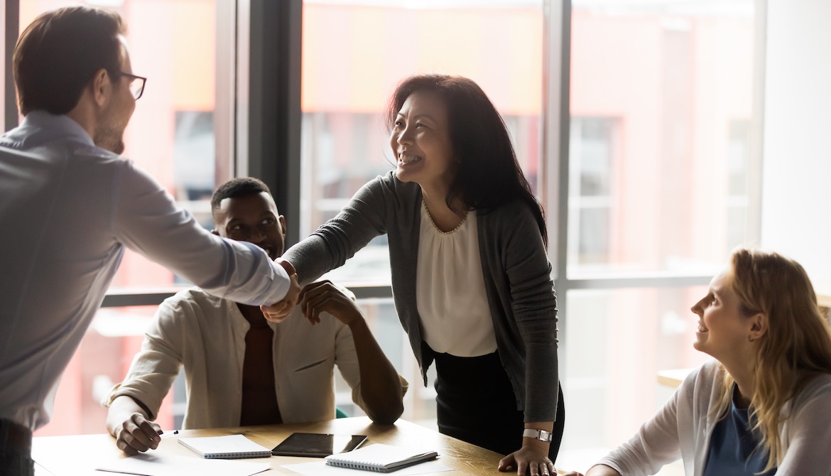 business manager recognizes employee during meeting by shaking hands