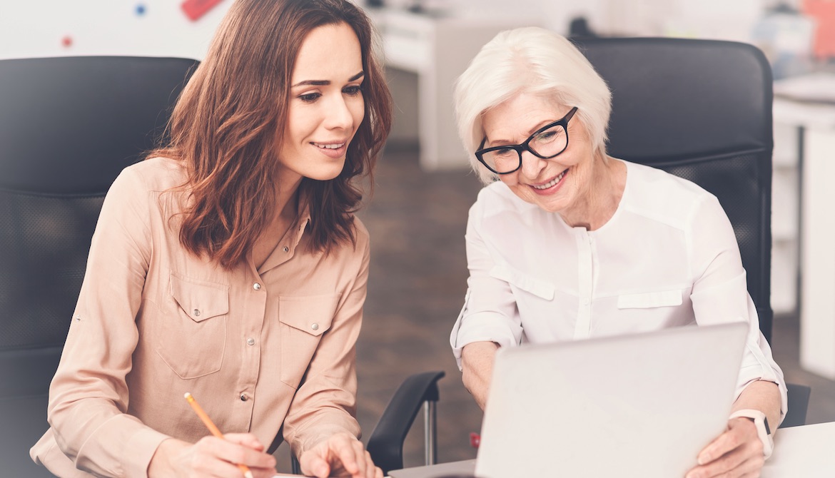 young female employee works in harmony with older baby boomer employee at the office