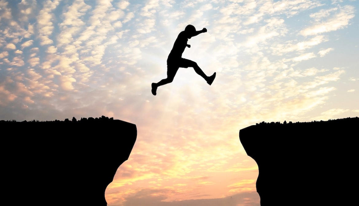 man jumping gap in mountains