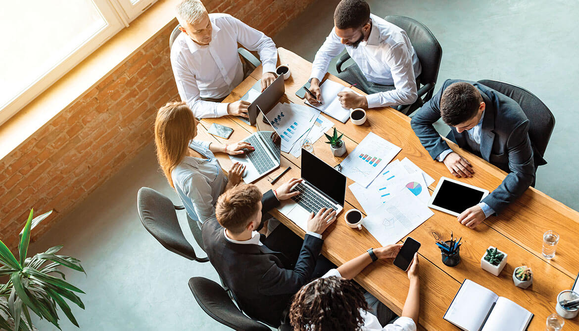 overhead view of diverse group of business colleagues working together at meeting table