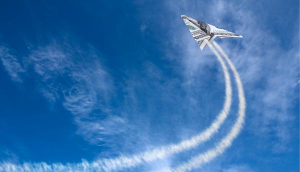 a paper airplane dollar flys through the sky