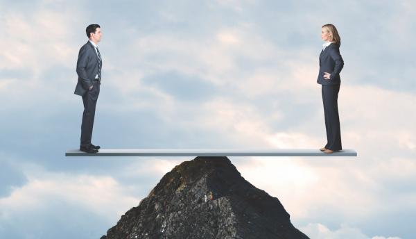 man and woman balance on top of a rock