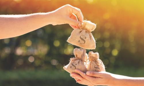 two hands exhanging a bag of money