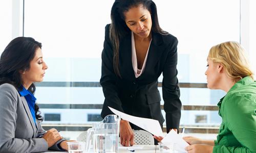 women sitting around desk going over papers