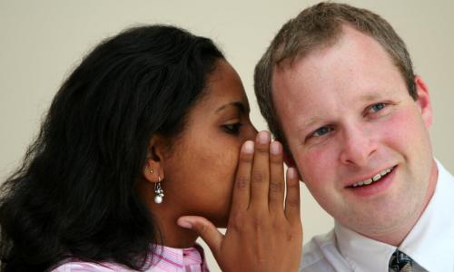 woman whispering in man's ear