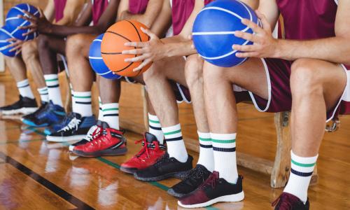 basketball players sitting on a bench holding basketballs