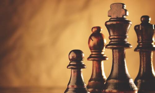 set of polished brown wooden chess pieces on a matching board