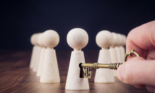 hand reaching out with a key to unlock the potential of one of several figurines representing employees