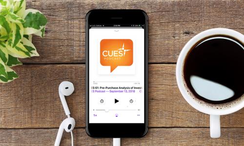 CUES Podcast on a mobile phone next to a cup of coffee